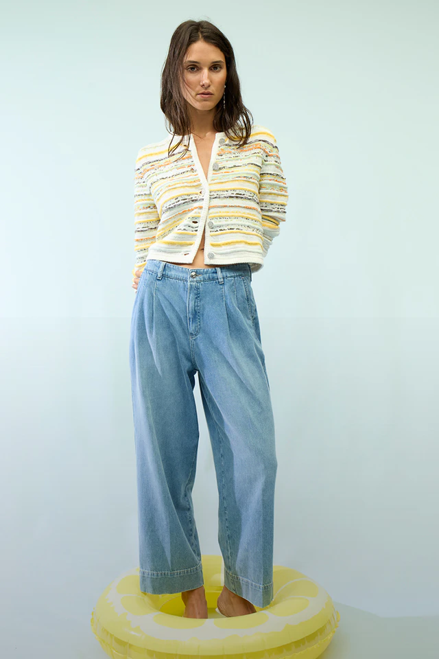 Frau trägt eine bunt gestreifte Strickjacke und eine lässige Jeans.