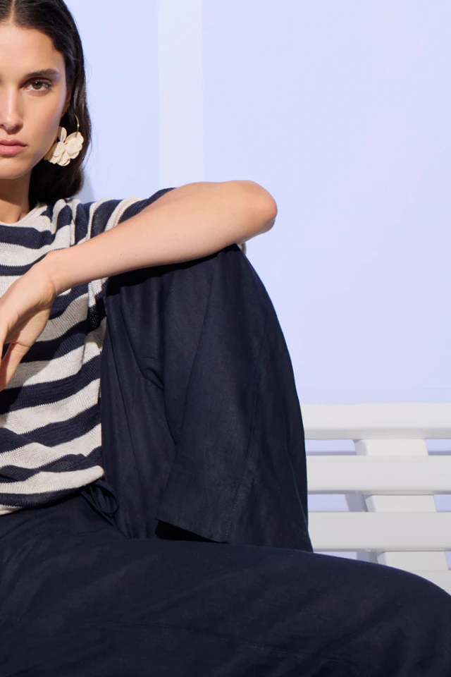 Frau mit einem weiss-blau gestreiften Pullover und einer dunkelblauen Hose.