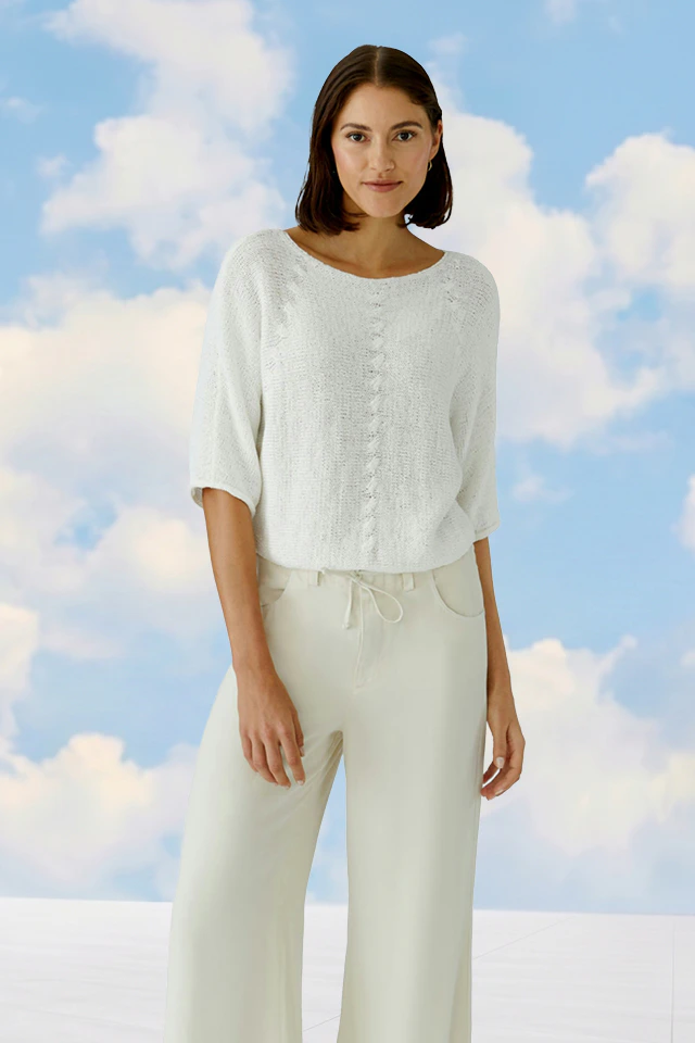 A woman wearing a white jumper and white jeans.