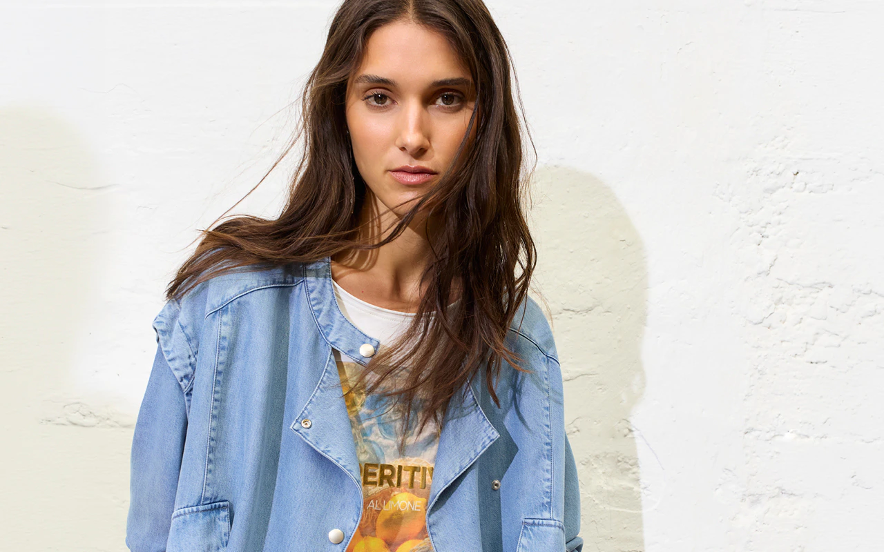Frau mit jeansjacke und bedruckten Shirt.