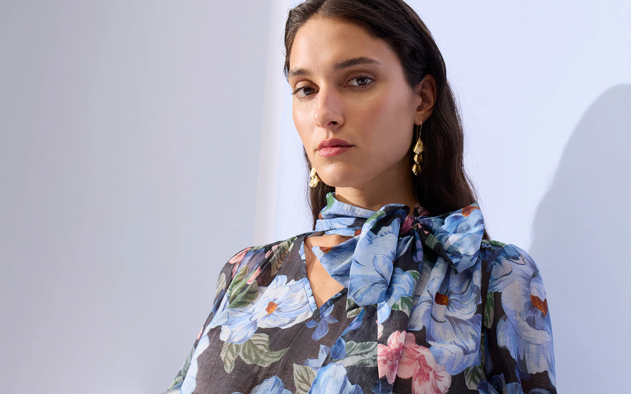 A woman is wearing a blouse with a dark background and a blue floral print.