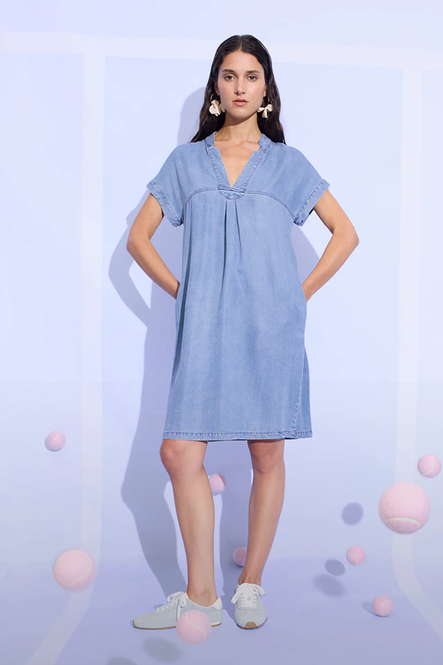 A woman is wearing a light blue, mid-length shift dress with a V-neck.