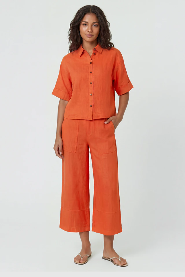 Frau trägt eine orange kurzarm Bluse und eine 7/8 Hose ebenfalls in orange.