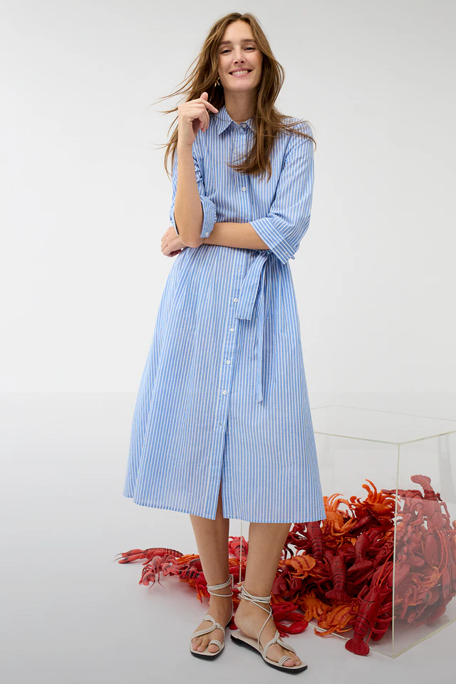 A woman is wearing a blue and white pinstriped midi dress.