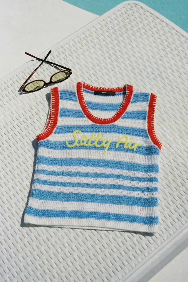Ein gelegtes Top in blau weiss gestreift mit roten Kanten und gelber Stickerei.
