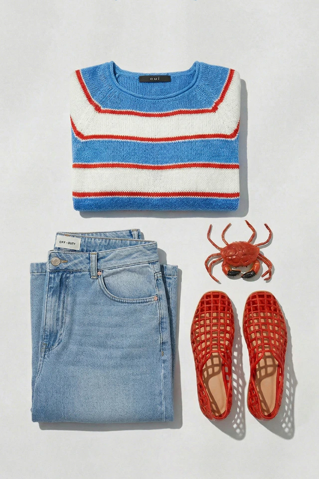 Zusammengelegte Kleidung oben gestreifter PUllover in weiß blau mit rot und darunter links eine jeans und rechts rote Schuhe.