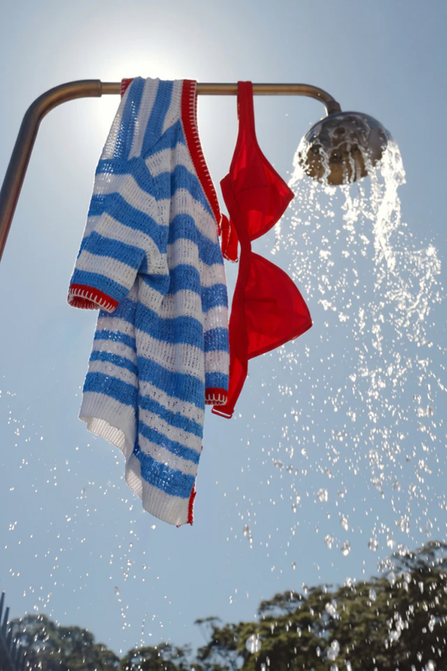 A blue and white striped top hangs over a shower with a red bikini top