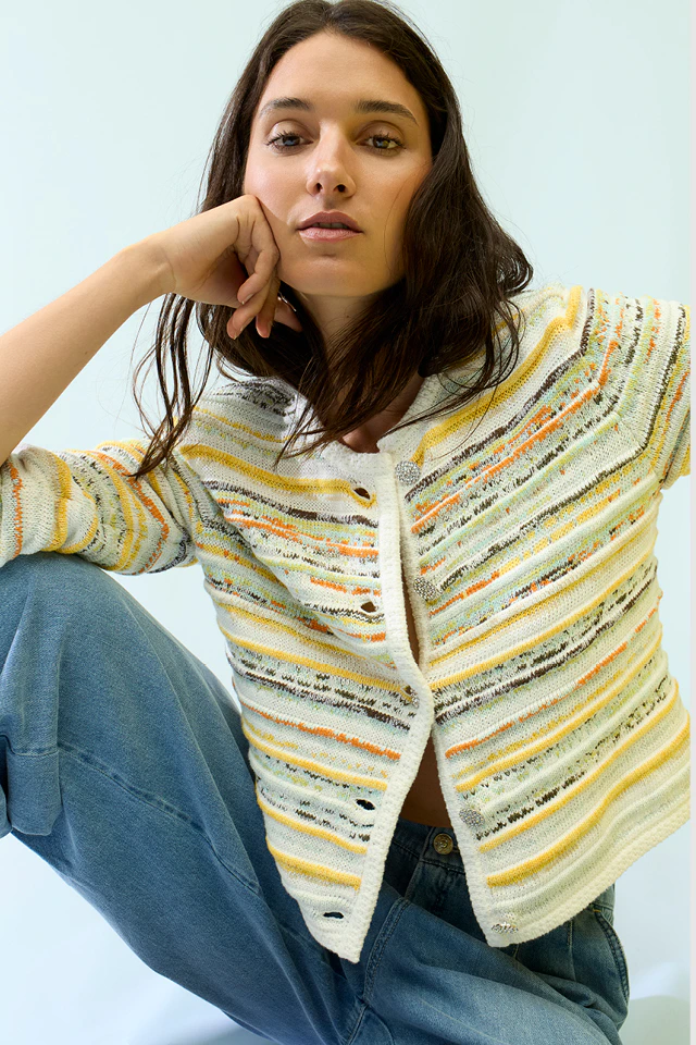 The model is wearing a yellow and white patterned cardigan with blue jeans