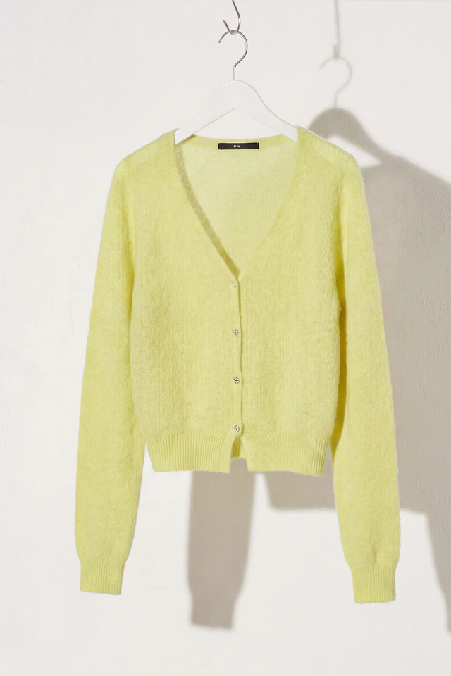 A light yellow cardigan is hanging on a hanger