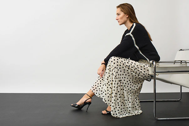 Model trägt schwarz-weiß gepunktetes Maxikleid mit schwarzem Pullover