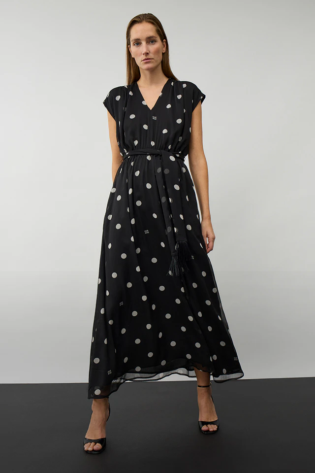 Frau mit schwarzem Kleid mit weissen Punkten in Midi-Länge.