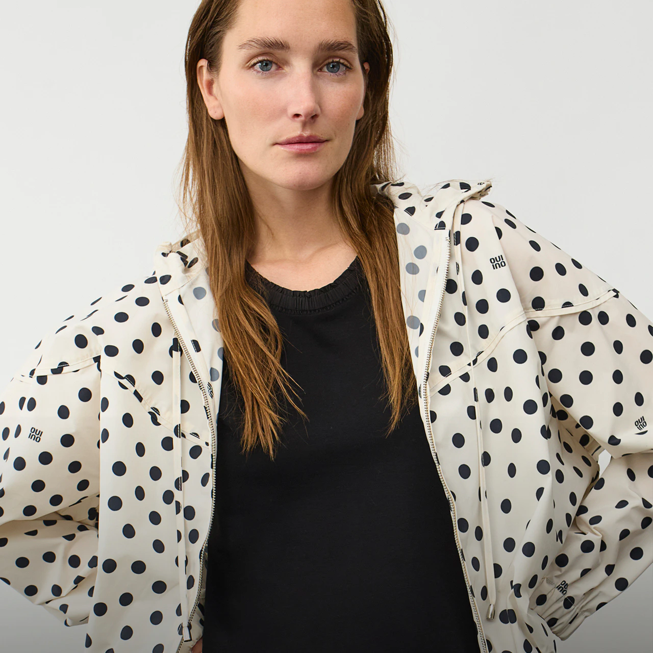 The model is wearing a black-and-white polka-dot windbreaker and a black T-shirt.