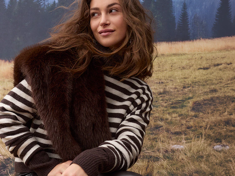 Autumn women’s fashion: A model is wearing a brown-and-white striped knitted jumper with a dark brown fur stole and black leather trousers.