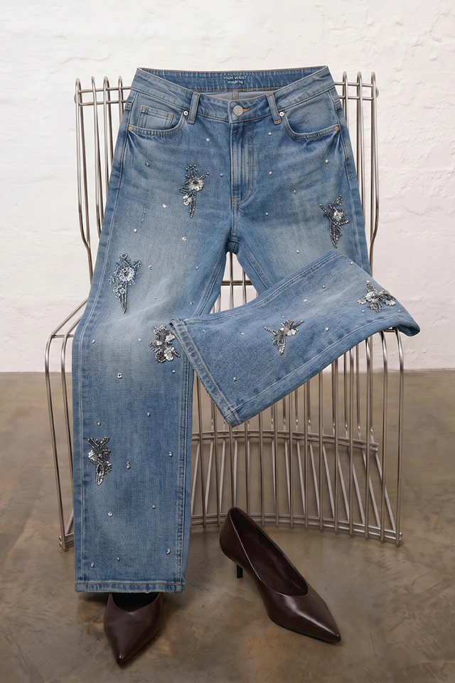 A pair of jeans thrown over a metal chair.