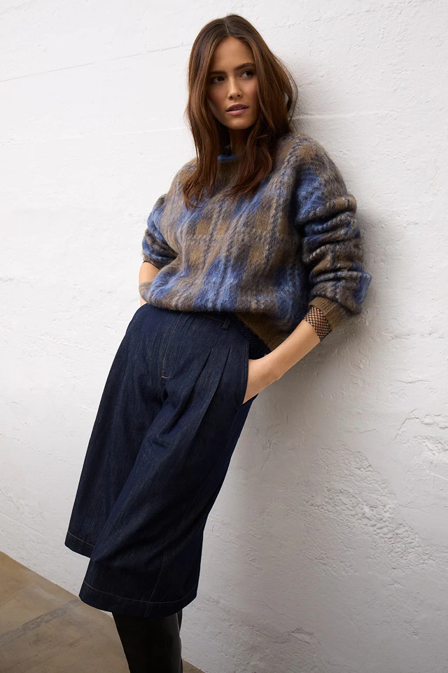 Frau trägt einen blau-braun gemusterten Oversize-Pullover mit dunkelblauer Hose.