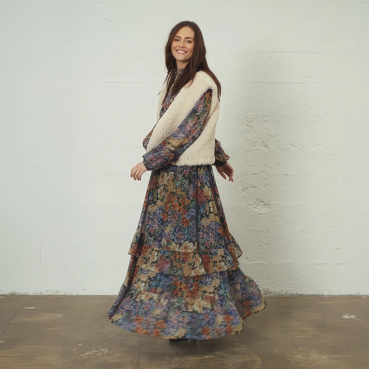 A woman wearing a floral midi dress and a beige waistcoat.