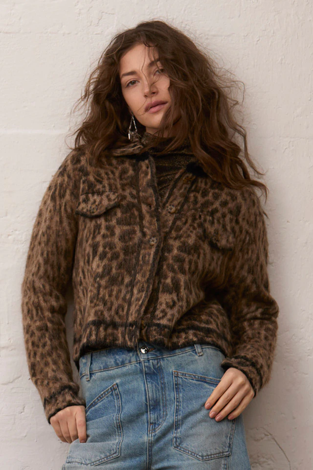 Model trägt eine braune Jacke mit Leo-Muster zu einem braunen Pullover, einer hellblauen Jeans im weiten Schnitt.