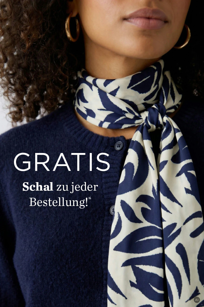 Model trägt einen dunkelblauen Strickpullover und ein cremefarbenes Tuch mit blauem Muster.