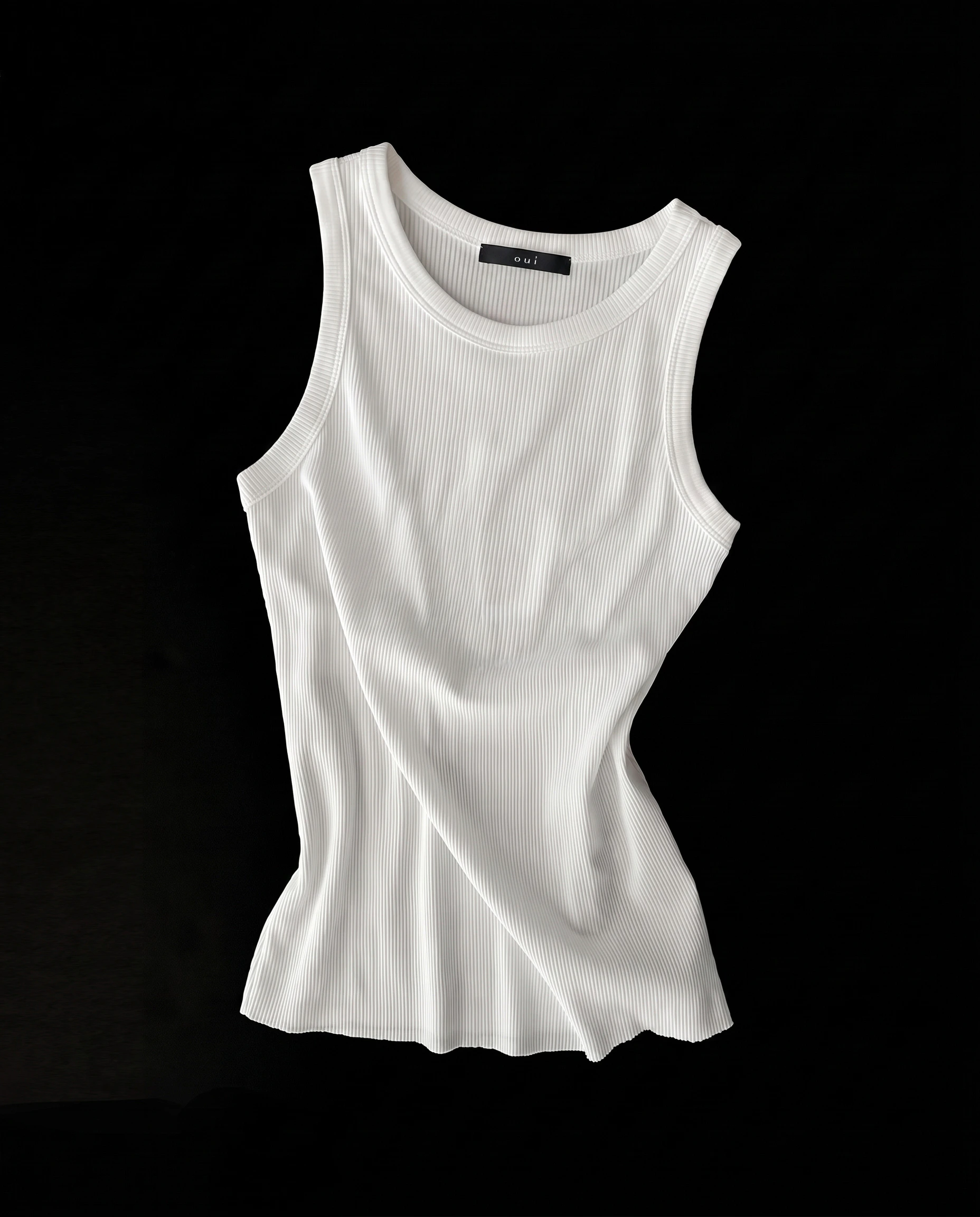 Oui Essentials: White ribbed tank top with a round neckline on a black background.