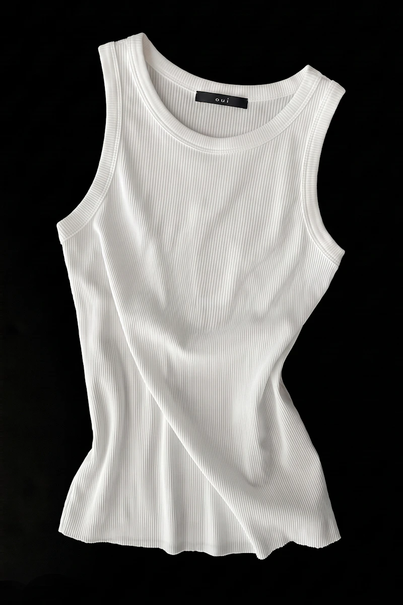 Oui Essentials: White ribbed tank top with a round neckline on a black background.