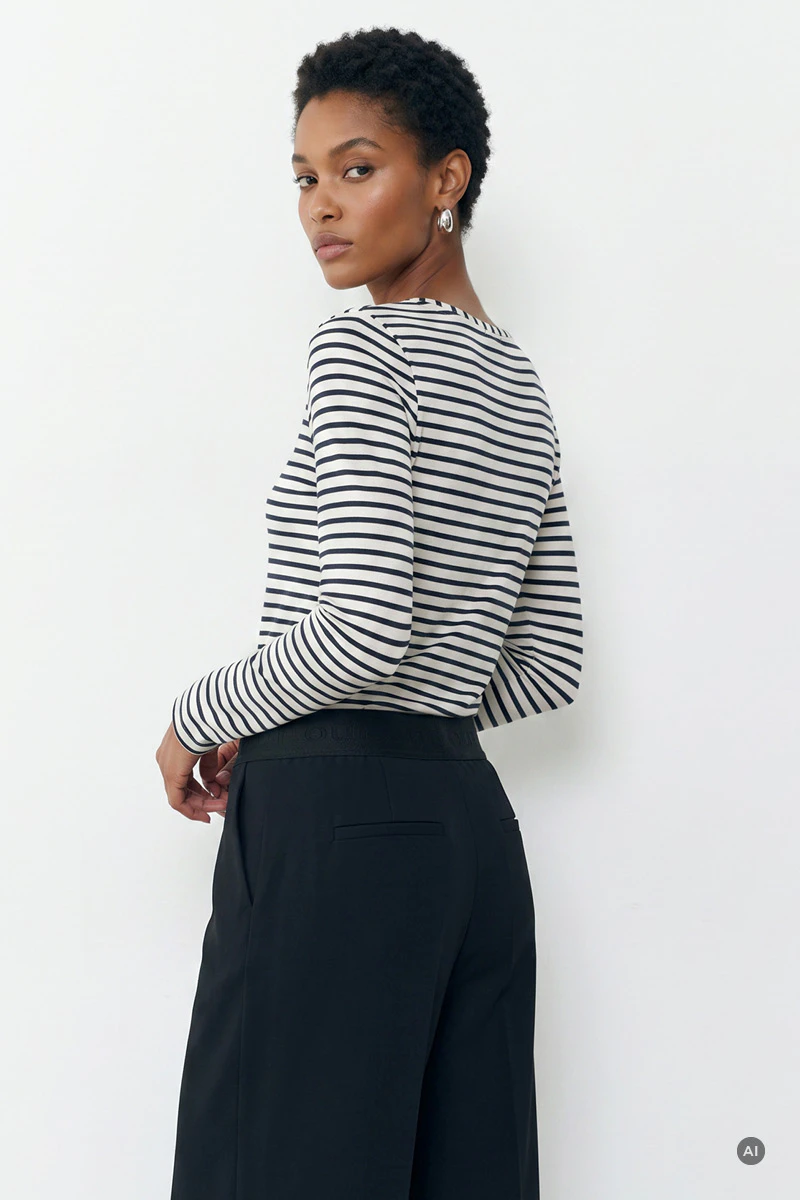 The model is wearing a white and blue striped long-sleeved top and loose-fitting dark blue trousers.