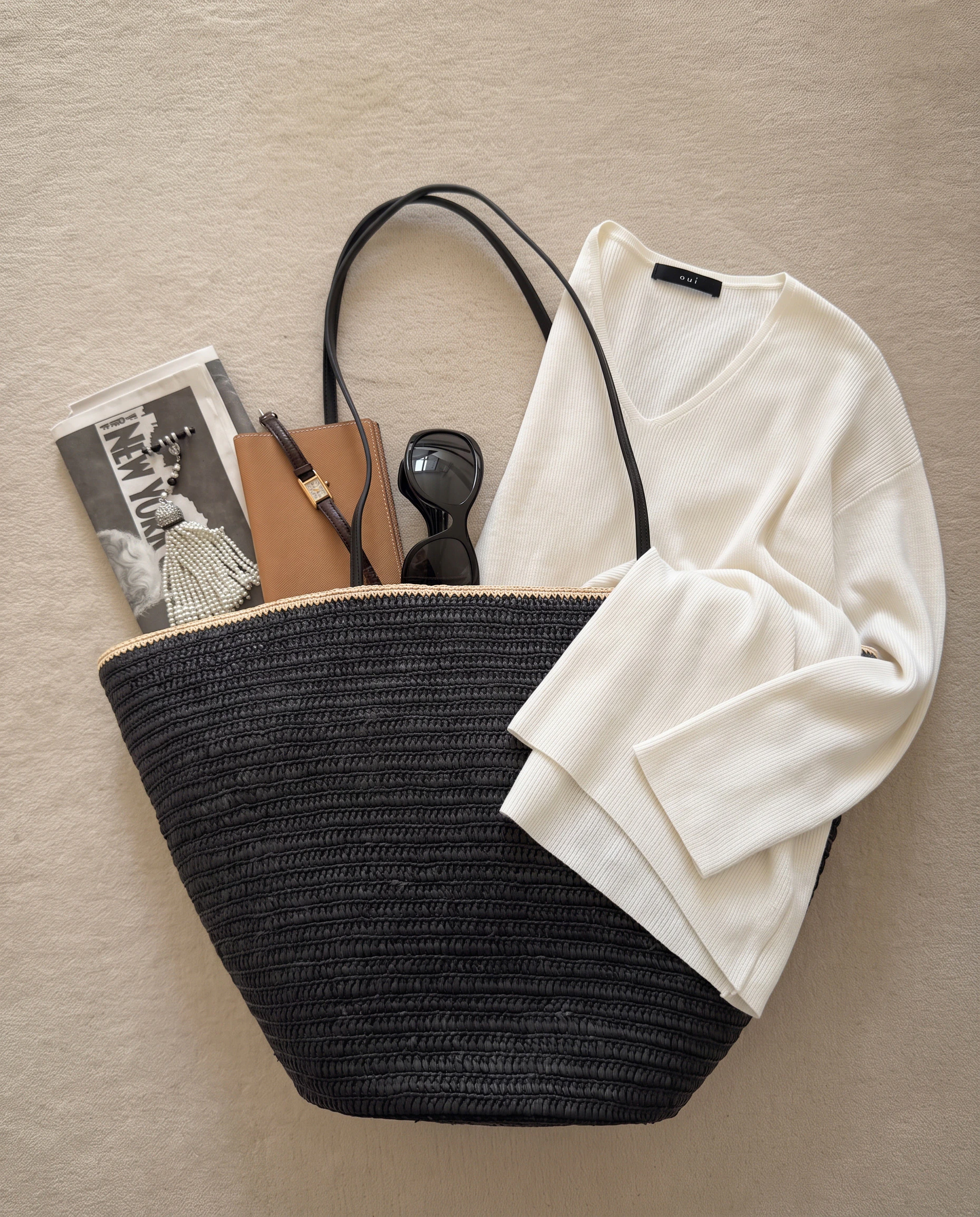 Oui Essentials: Weißer gerippter Pullover mit V-Ausschnitt, kombiniert mit einer schwarzen Tasche und Accessoires.