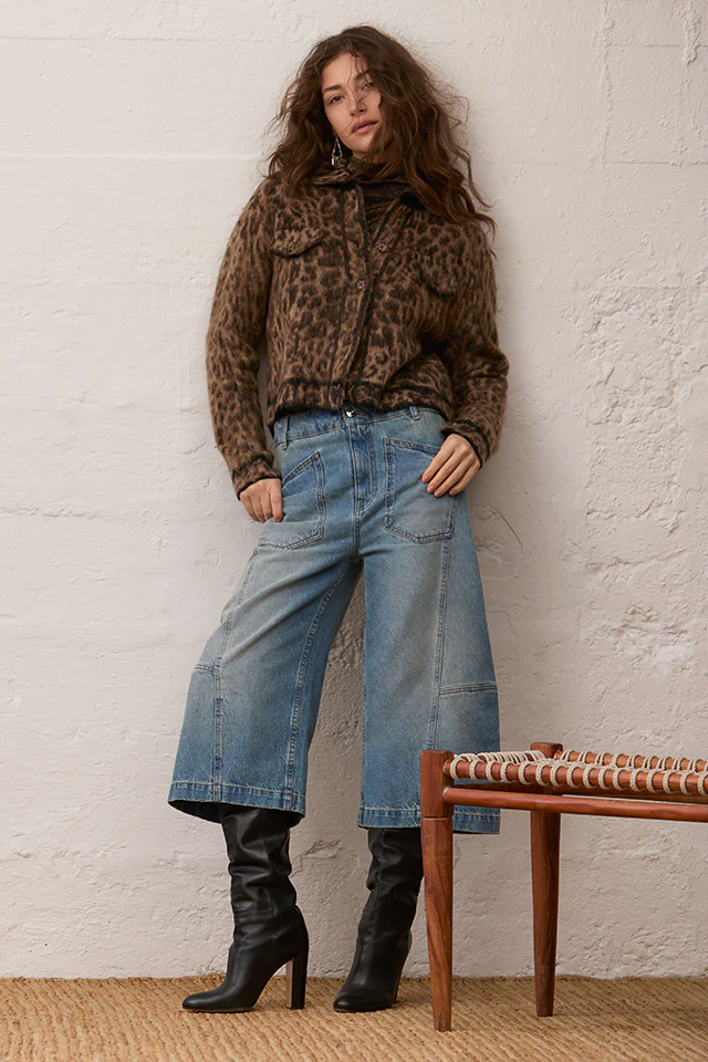 Model trägt eine braune Jacke mit Leo-Muster zu einem braunen Pullover, einer hellblauen Jeans im weiten Schnitt.