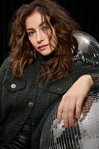 A dark green cardigan with a lace blouse and black leather trousers