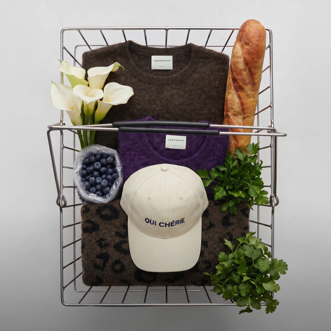 Cashmere jumpers, knitted jumpers and a cap from Oui, presented in an inspiring way in the shopping basket.