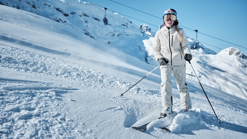 Skifahren lernen; eine Skifahrerin steht lachend vor dem Sessellift; Schöffel