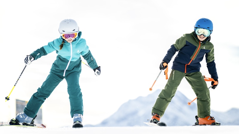 Skifahren lernen; zwei Kinder haben sichtlich Freude bei ihren ersten Übungen auf Skiern; Schöffel