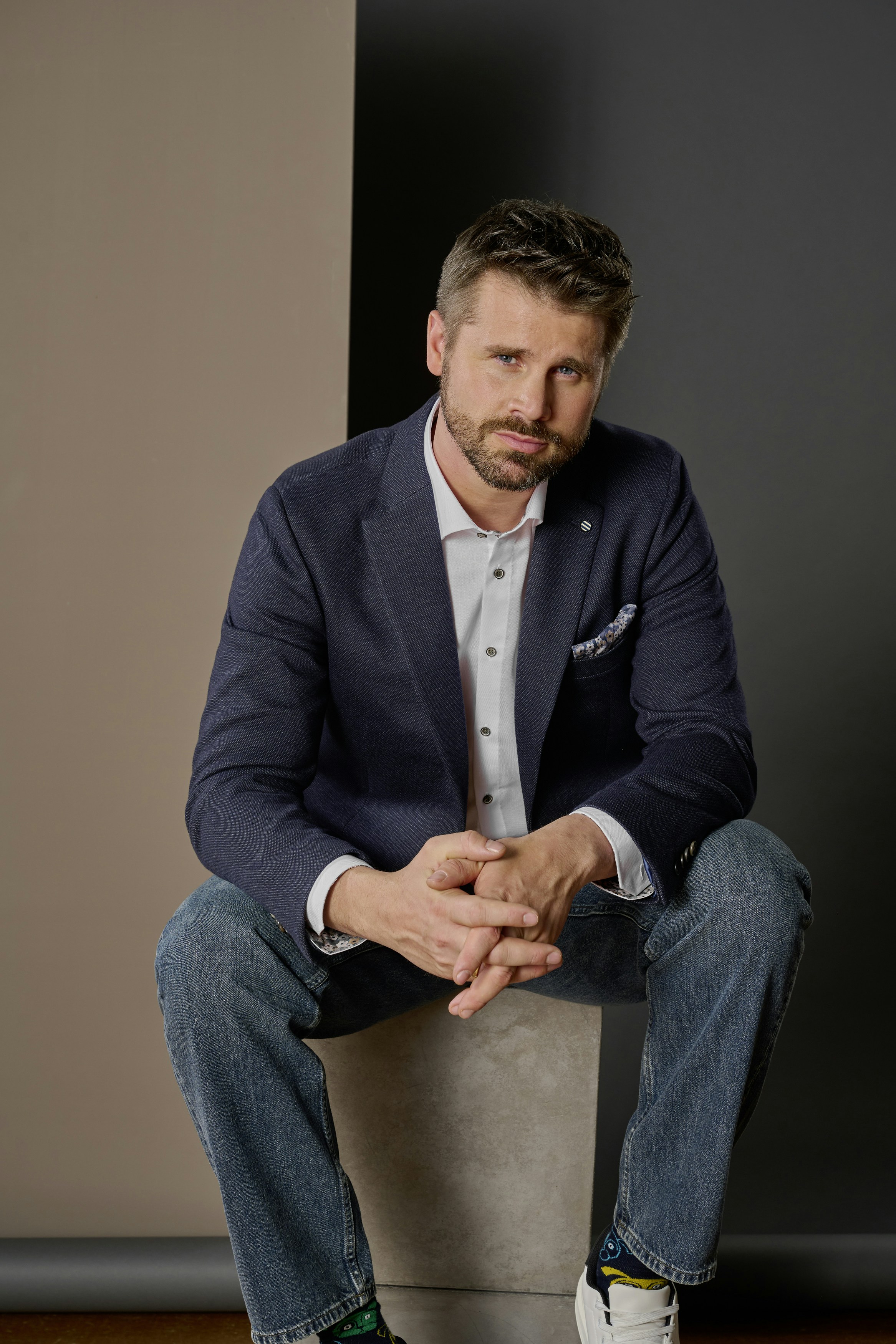Thore Schölermann sitzt mit einem blauem Sakko von VENTI auf einem Sockel