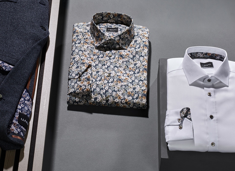 Eine Kobination aus verschiedenen Hemden und einem blauem sportlichem Sakko von VENTI liegen auf dem Tisch.