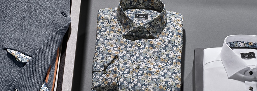 Eine Kobination aus verschiedenen Hemden und einem blauem sportlichem Sakko von VENTI liegen auf dem Tisch.