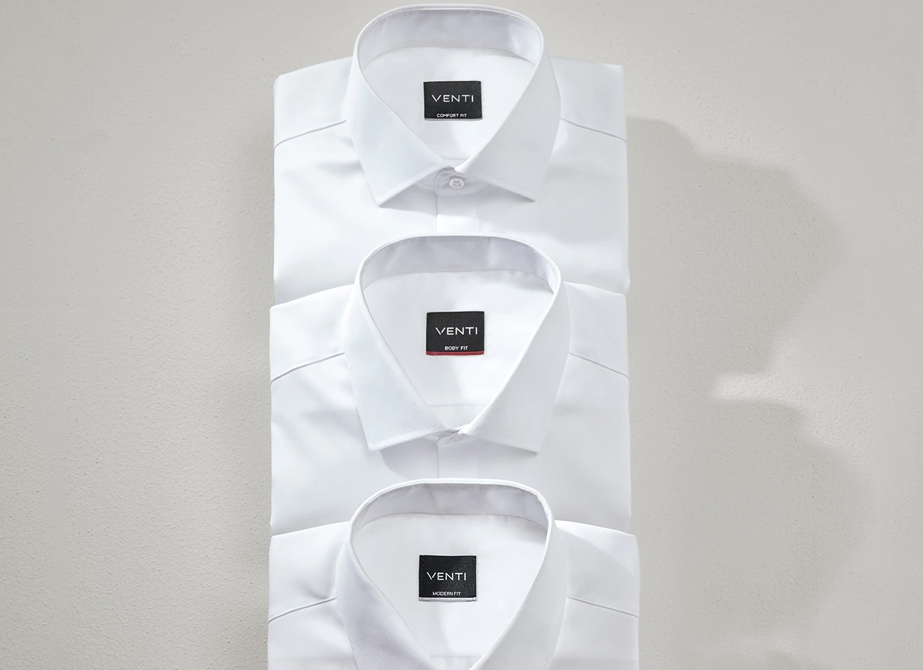 Drei weiße Hemden übereinandergelegt, jeweils mit Kragen und sichtbarem VENTI-Label mit den Bezeichnungen Comfort Fit, Body Fit und Modern Fit
