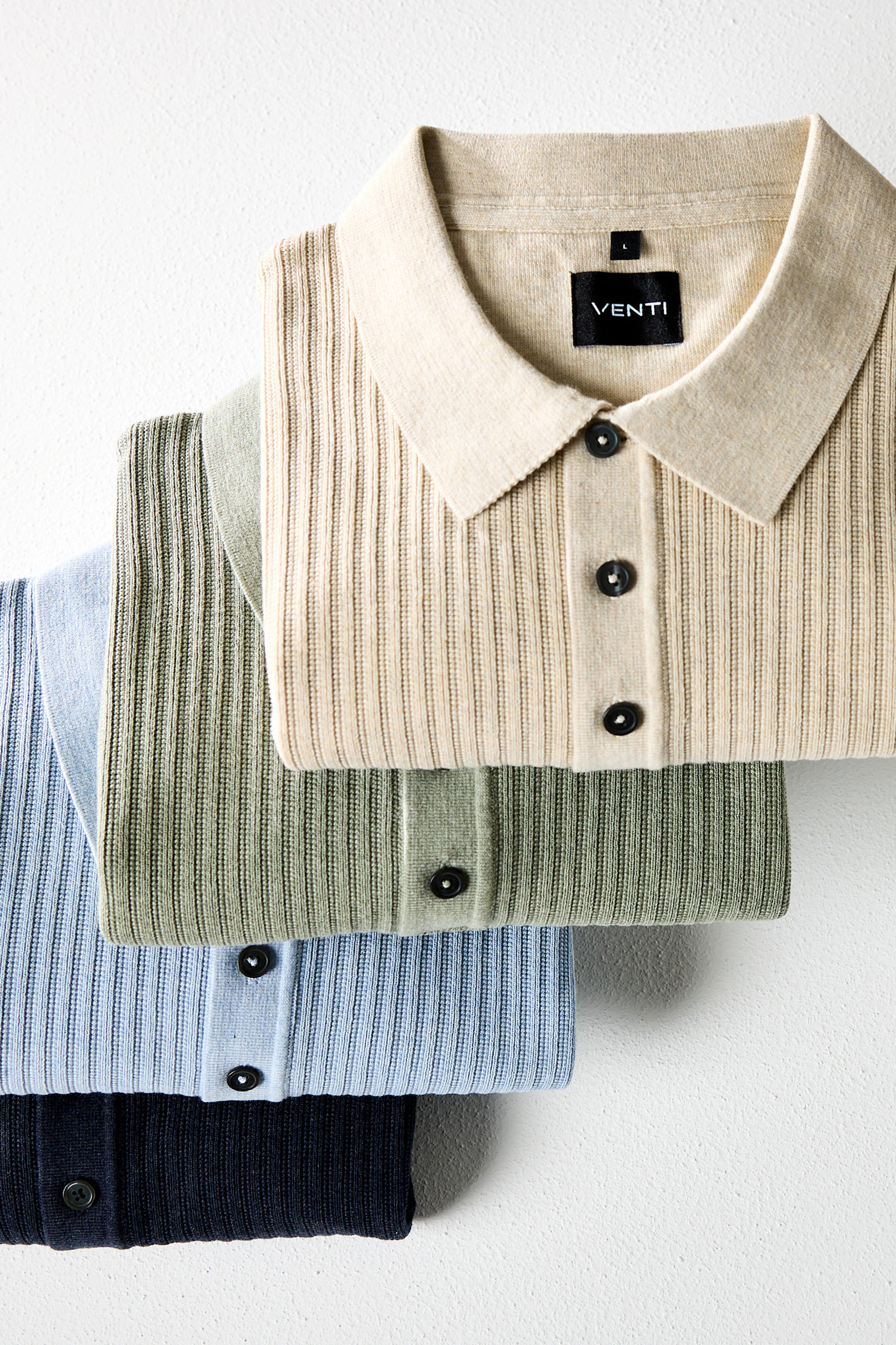 Langarm-Poloshirts in Beige, Grün, Hellblau und Dunkelblau liegen gestapelt.